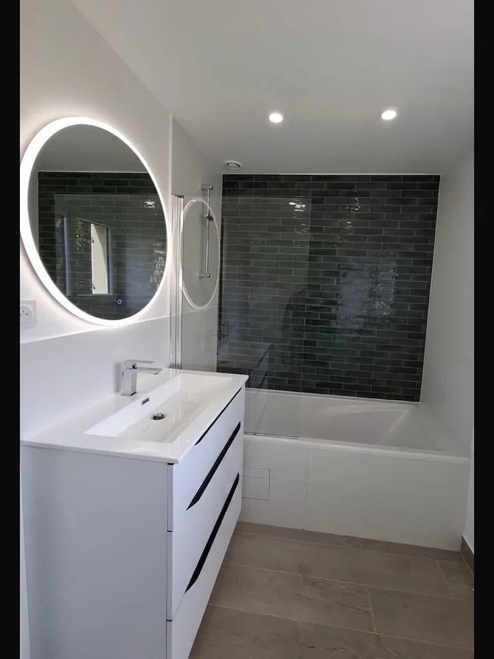 Après rénovation — salle de bain avec baignoire, faïence anthracite et miroir LED