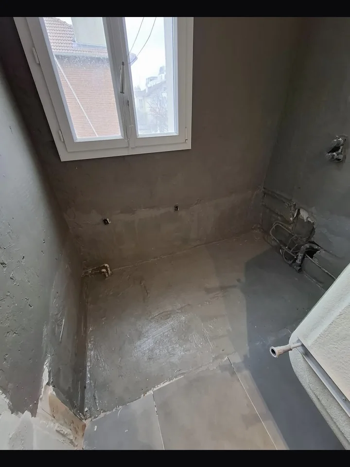 Avant rénovation — pièce brute enduit gris plomberie apparente